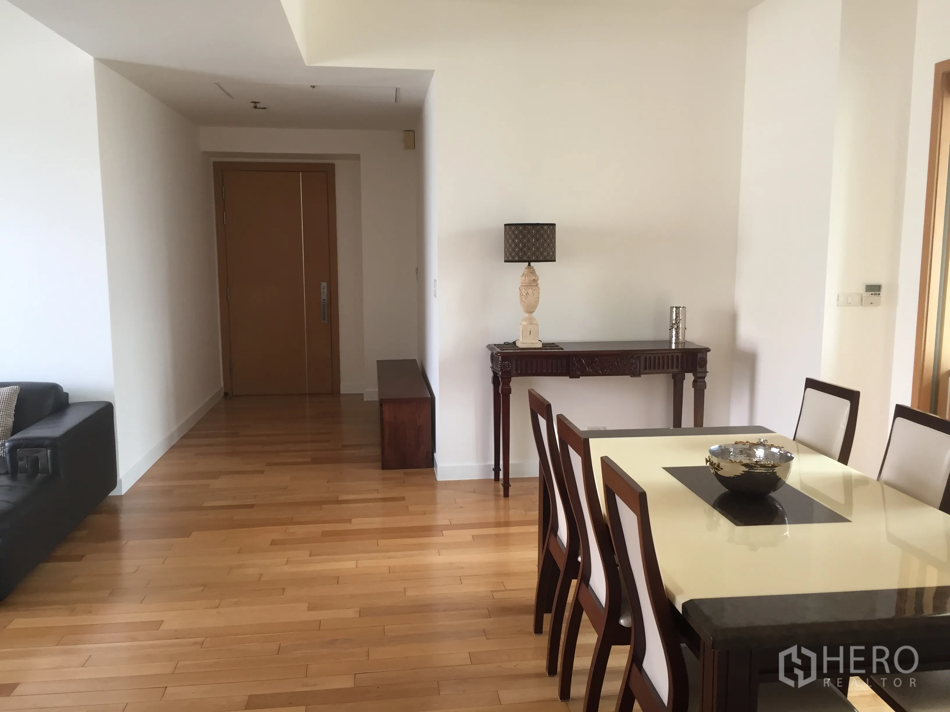 Condominium for rent in Khlong Toei, Bangkok - Dining area with six-seat table, entry hallway, and console table on light hardwood flooring.