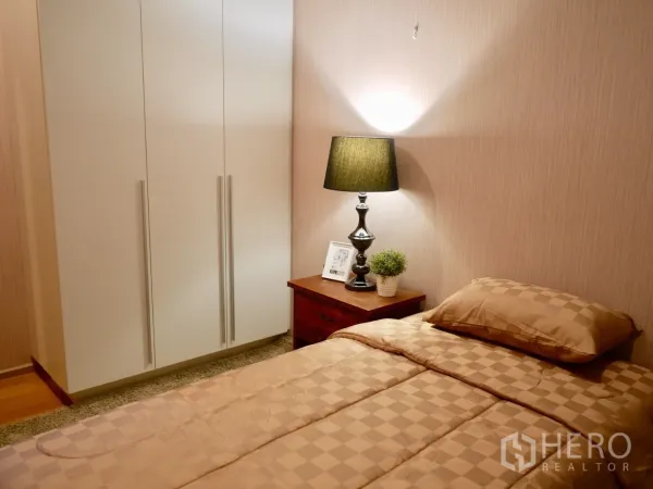 Condominium for rent in Watthana, Bangkok - Cozy second bedroom with wardrobe, bedside table and warm lighting.