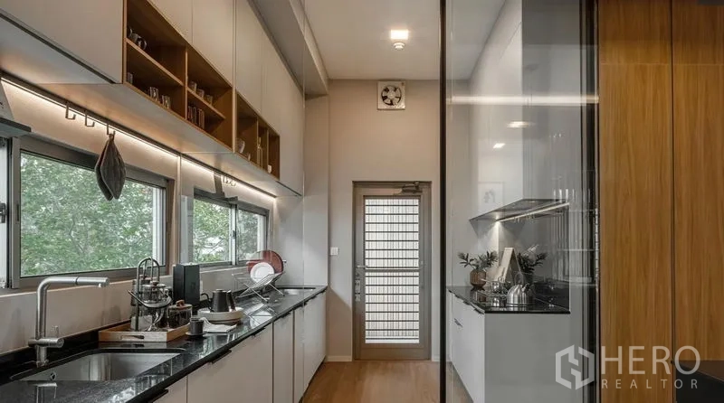 独立式住宅 出租在Saphan Sung, Bangkok - 现代长廊式厨房，黑色花岗岩台面与玻璃隔断