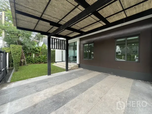 Detached House for rent in Bang Kapi, Bangkok - Covered carport beside a neat lawn and entry steps along the side of the house.