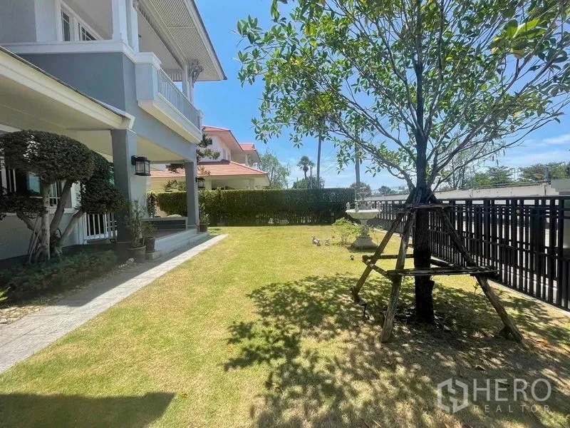 บ้าน ขายในSamut Prakan - สนามหญ้ากว้างหน้าบ้าน มีต้นไม้ใหญ่ รั้วเหล็ก และเฉลียงร่มรื่น