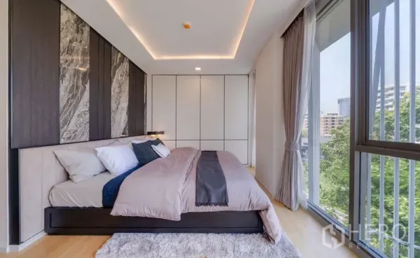 公寓 出售在Watthana, Bangkok - 主卧采光充足，落地窗与绿色城市景观，石纹床头与内置衣柜。