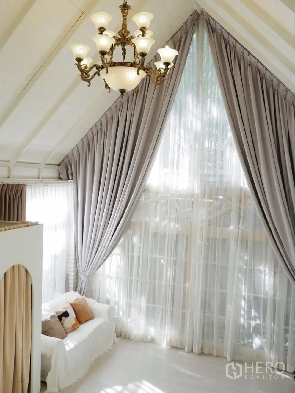 Detached House for rent in Phra Khanong, Bangkok - Bright room with vaulted ceiling, chandelier, tall drapes and a sofa.