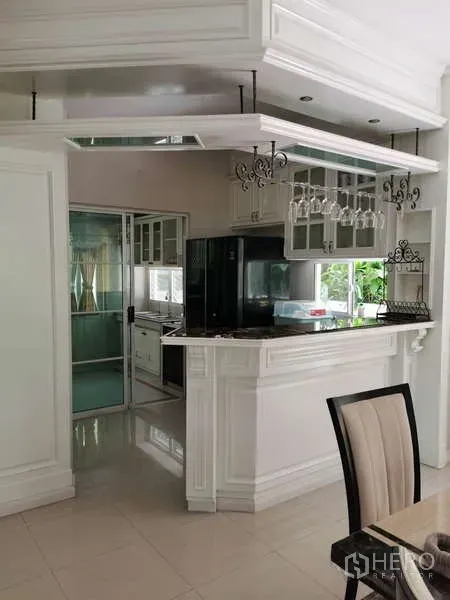 Detached House for rent - Bright pantry and breakfast bar with white cabinetry, hanging wine glasses, and a black refrigerator next to the dining area.
