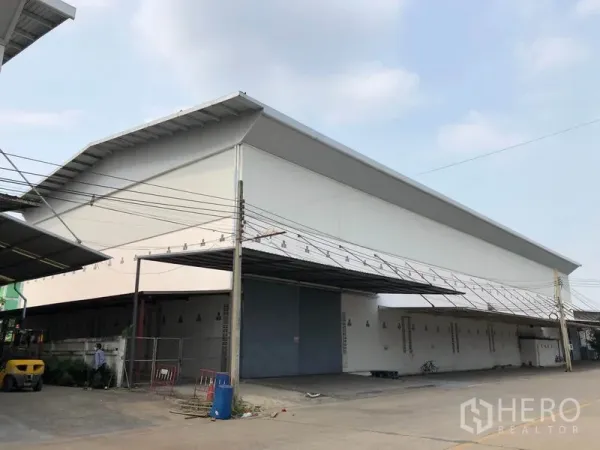 Factory for rent in Bang Bua Thong, Nonthaburi - Corner perspective of high‑gabled factory building with oversized entry door.