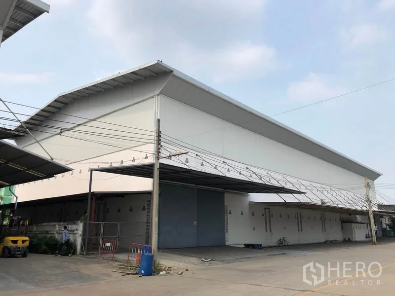 Factory for rent in Bang Bua Thong, Nonthaburi - Corner perspective of high‑gabled factory building with oversized entry door.