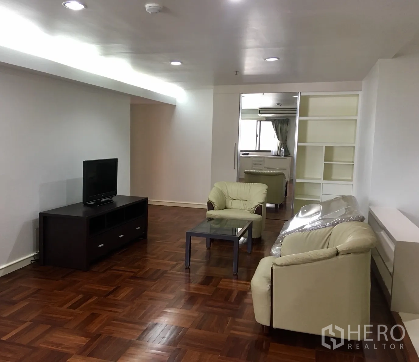 Condominium for rent or sale in Watthana, Bangkok - Living area with leather sofa set, TV console and recessed lighting.
