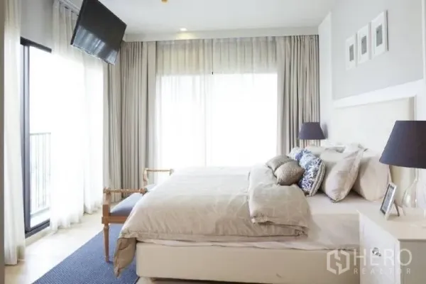 Condominium for rent in Bangkok - Sunlit master bedroom with king bed, floor-to-ceiling curtains and balcony access in a Phrom Phong condo.