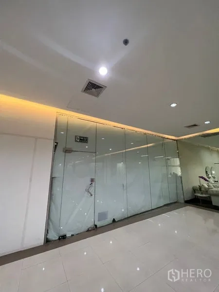 Retail Space for rent - Full-height glass shopfront facing a polished corridor with ceiling downlights, ideal for signage and display.