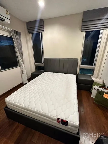 Detached House for rent in Bang Phli, Samut Prakan - Upper-floor bedroom with wood flooring, upholstered bed and corner windows with Roman blinds.
