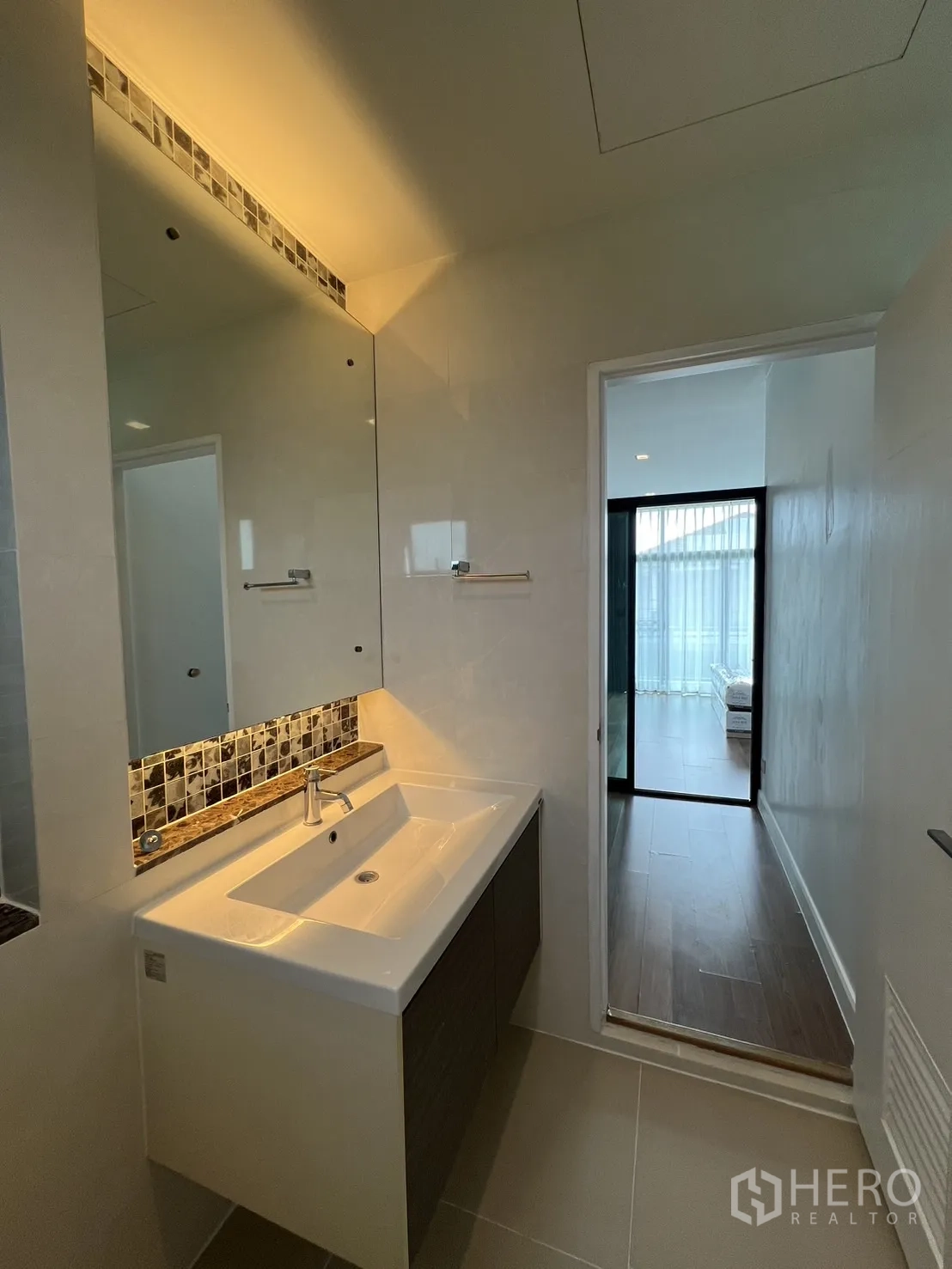 Detached House for rent in Bang Kapi, Bangkok - Vanity counter with backlit mirror inside a bright bathroom.
