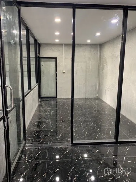 Warehouse for rent in Khan Na Yao, Bangkok - Another angle of the glass-partitioned office featuring glossy marble-look tiles and ceiling lights.