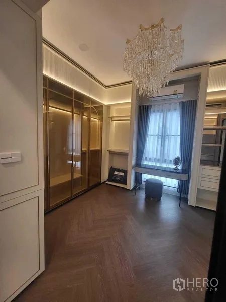 Detached House for rent in Saphan Sung, Bangkok - Walk-in closet with glass wardrobes, chandelier and herringbone wood floor.