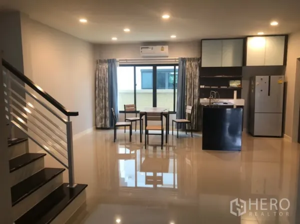 Detached House for rent or sale in Bang Kapi, Bangkok - Bright open-plan living and dining area with staircase, recessed lighting and sliding glass doors.