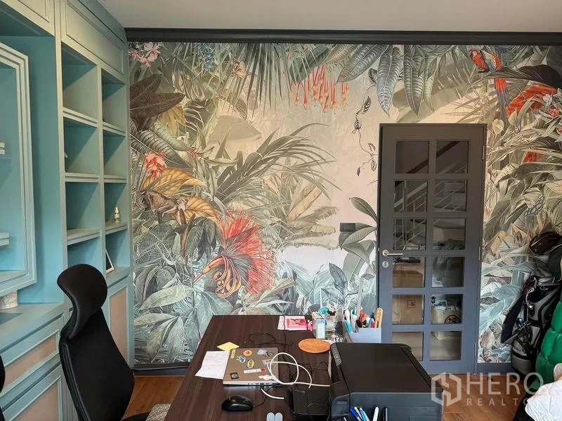 Detached House for rent in Bang Kapi, Bangkok - Home office with tropical botanical mural and pastel built‑in shelving.