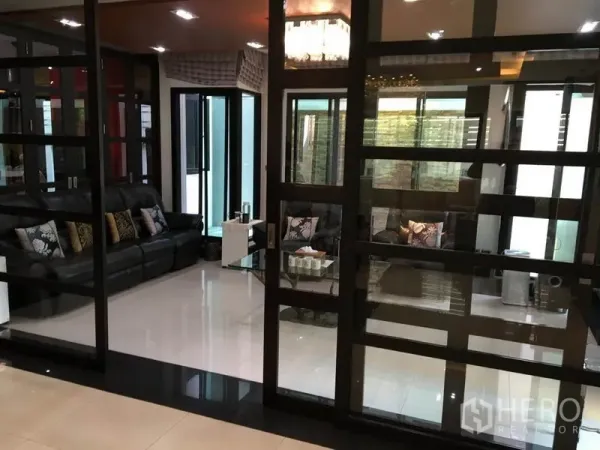 บ้าน ให้เช่าในKhlong Toei, Bangkok - ห้องนั่งเล่นกั้นกระจก โซฟาหนังสีดำ และพื้นกระเบื้องเงา