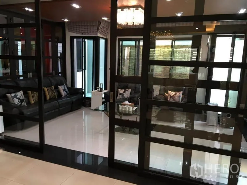 บ้าน ให้เช่าในKhlong Toei, Bangkok - ห้องนั่งเล่นกั้นกระจก โซฟาหนังสีดำ และพื้นกระเบื้องเงา
