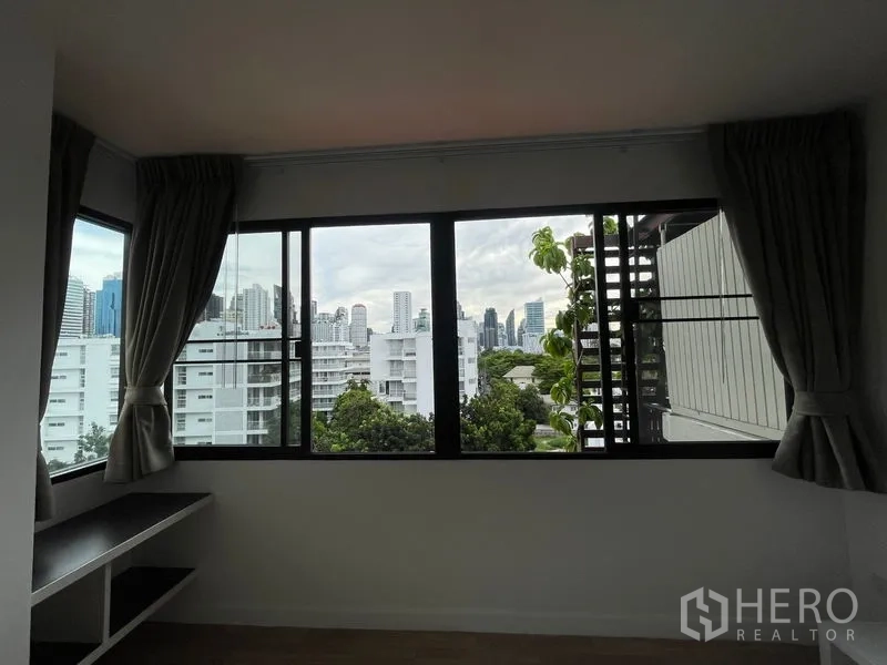 Condominium for rent in Watthana, Bangkok - Bedroom window framing Bangkok skyline above built-in desk.