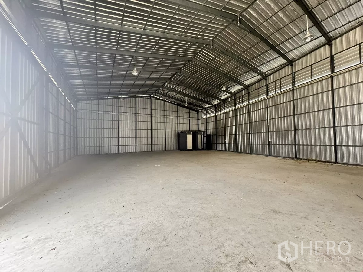 Warehouse for rent in Bang Lamung, Chon Buri - Open-plan storage hall with level concrete slab, ridge roof and restrooms positioned at the rear.