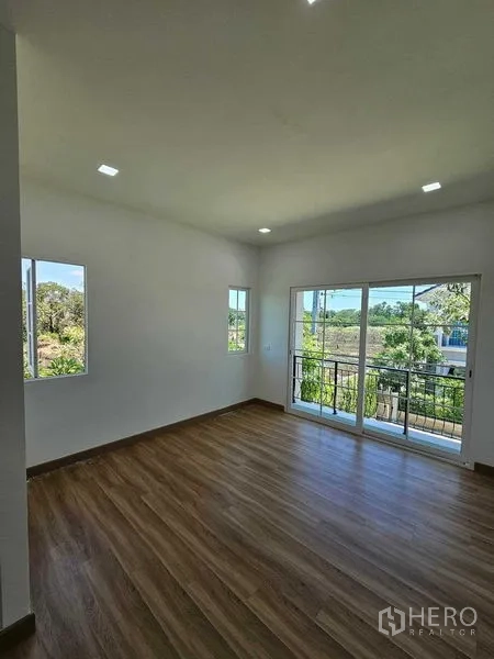Detached House for rent in Thanyaburi, Pathum Thani - Spacious bedroom with large windows and balcony access over greenery