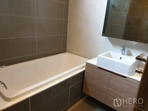 公寓 出租在Watthana, Bangkok - 浴室配全尺寸浴缸、悬挂式柜体、方形面盆与镜柜。