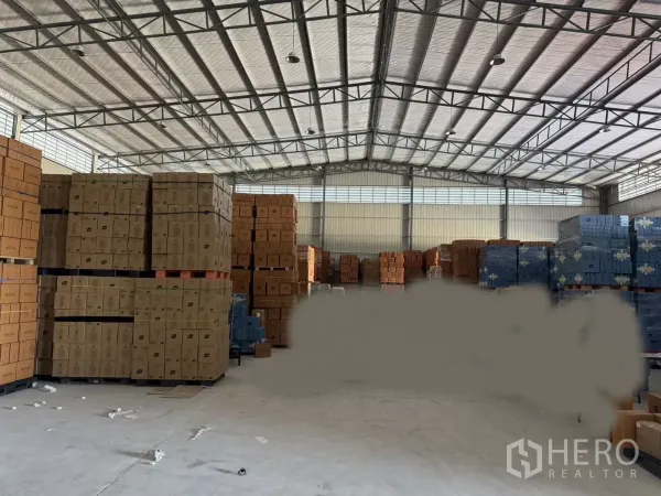 Warehouse for rent in Bang Bo, Samut Prakan - Spacious warehouse interior with high insulated steel roof, stacked pallets and a concrete floor for bulk storage.