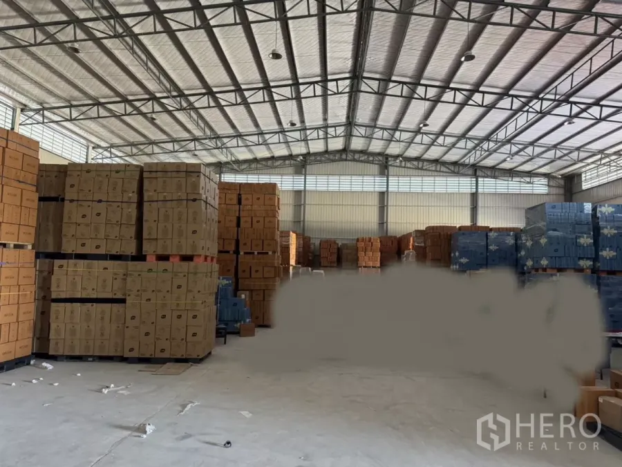 Warehouse for rent in Bang Bo, Samut Prakan - Spacious warehouse interior with high insulated steel roof, stacked pallets and a concrete floor for bulk storage.