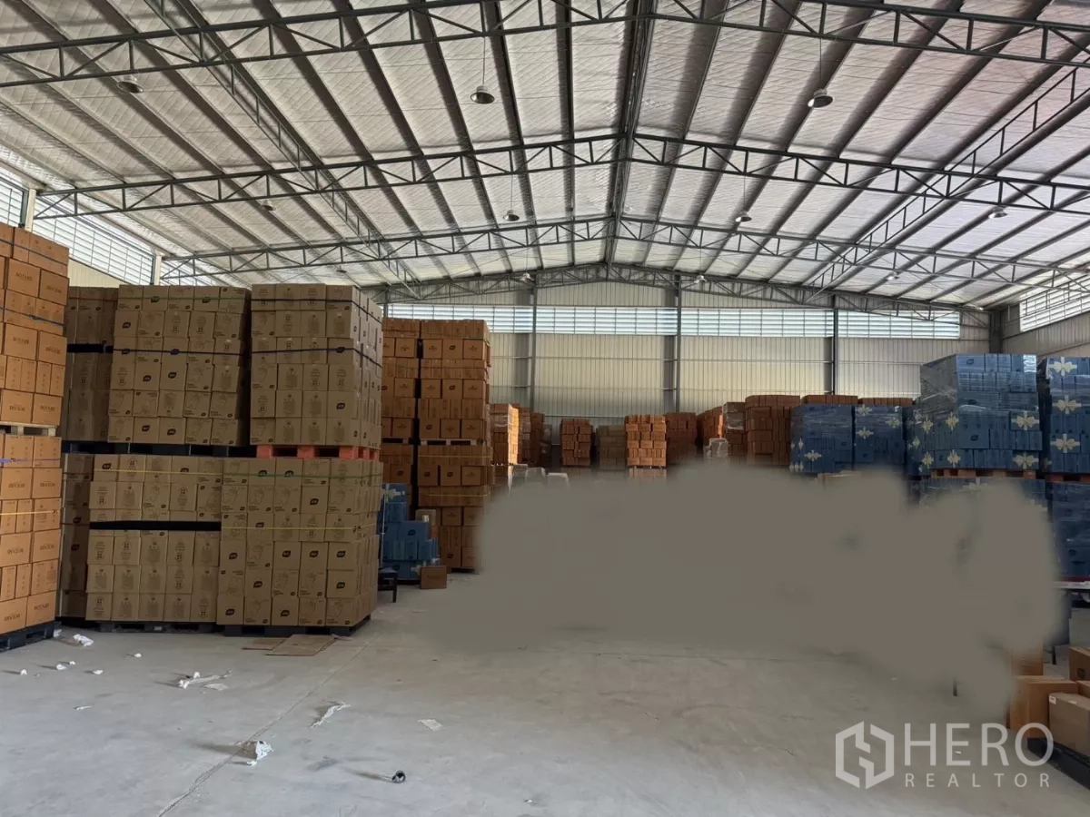Warehouse for rent in Bang Bo, Samut Prakan - Spacious warehouse interior with high insulated steel roof, stacked pallets and a concrete floor for bulk storage.