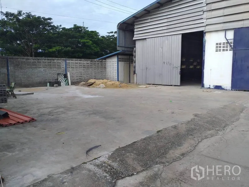 คลังสินค้า ให้เช่าในPak Kret, Nonthaburi - มุมด้านข้างโกดัง ประตูม้วนขนาดใหญ่ และลานปูคอนกรีตเหมาะสำหรับรถบรรทุก
