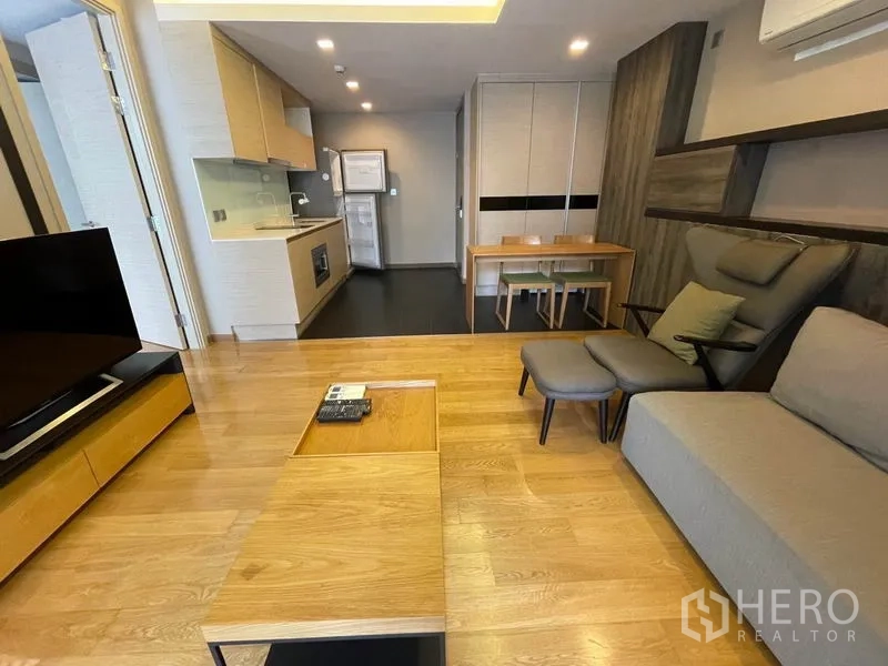 公寓 出售在Watthana, Bangkok - 现代公寓的休闲角，带嵌入式层架、餐桌与小厨房。