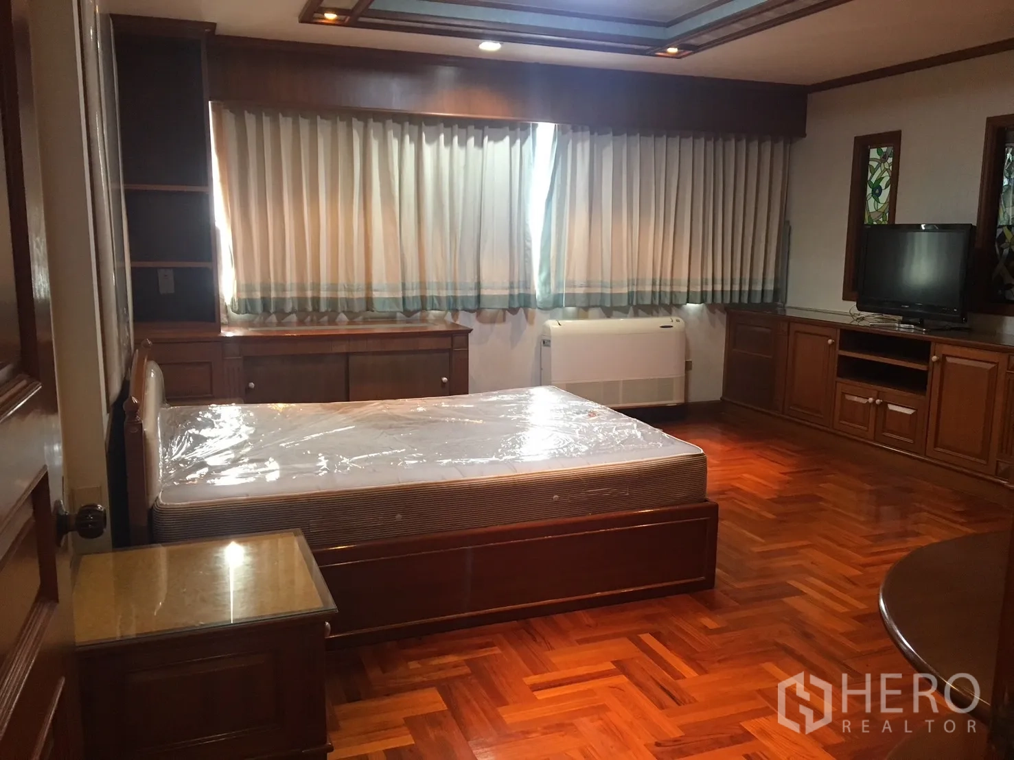公寓 出租在Watthana, Bangkok - 主卧带木质柜体、拼花地板、大窗及电视柜。