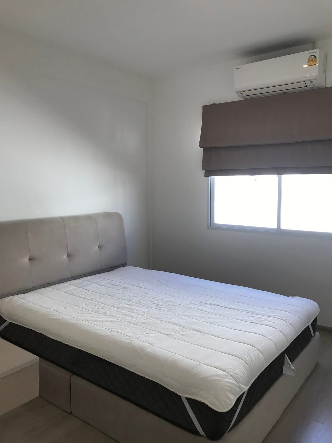 联排别墅 出租在Prawet, Bangkok - 明亮卧室，软包床、窗户与空调。