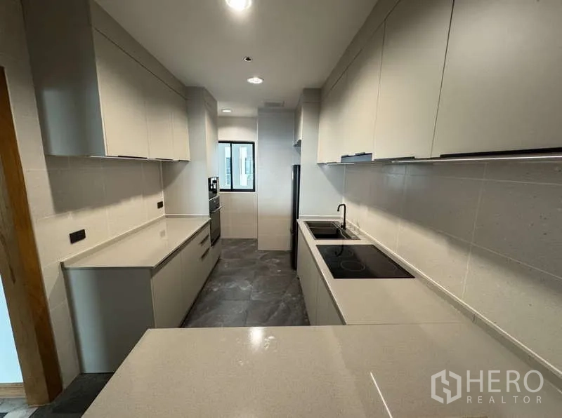 Condominium for rent - Modern kitchen from opposite angle showing dual sinks, oven and long countertops.