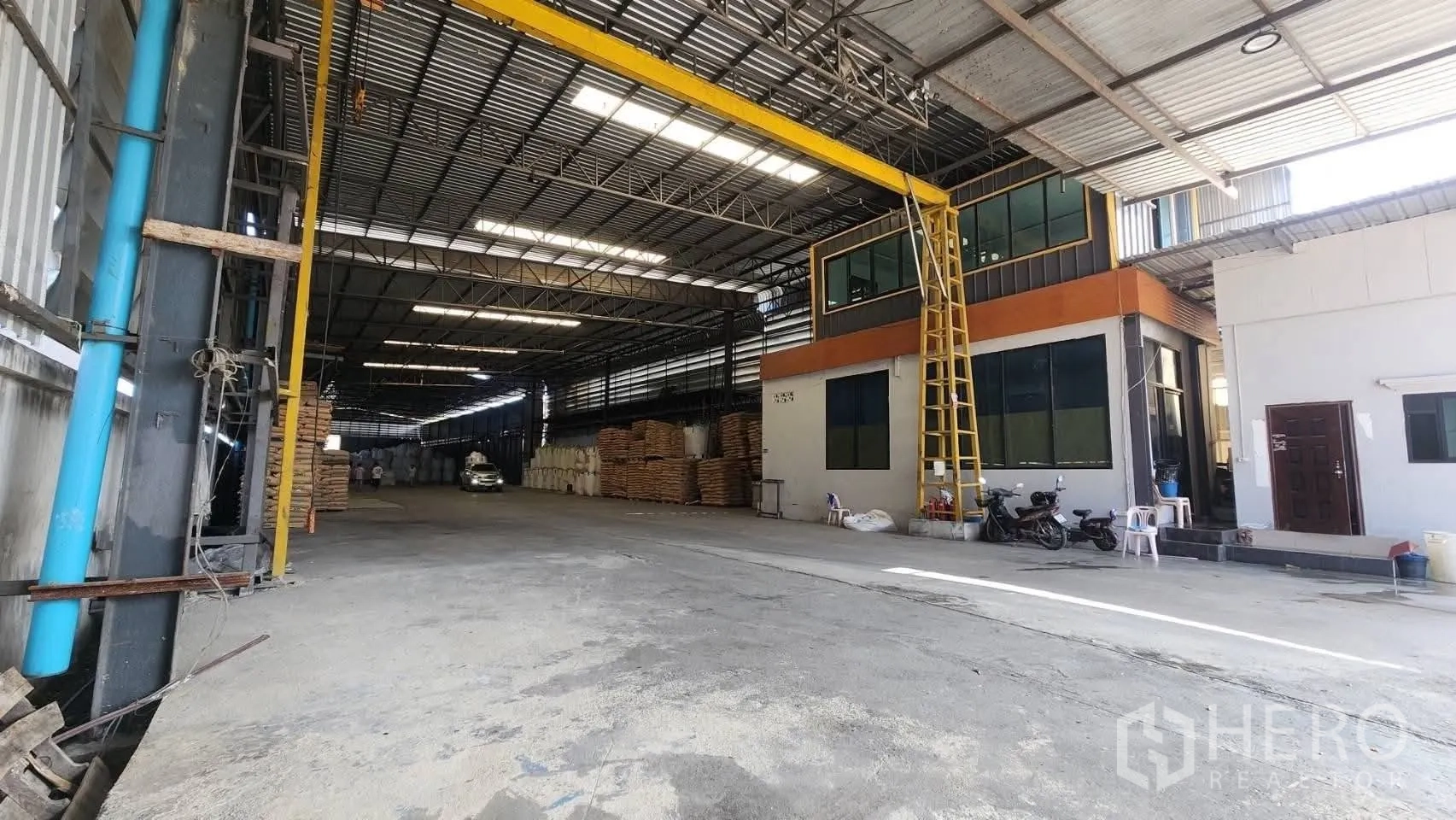 Warehouse for rent in Bang Phli, Samut Prakan - Loading area showing an overhead gantry beam with hoist beside an attached office block and space for equipment.