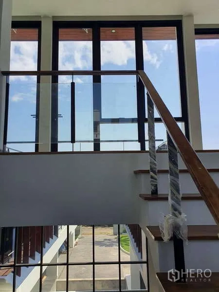 Detached House for rent in Phra Khanong, Bangkok - Stairwell with floor-to-ceiling windows and a glass handrail bringing natural light.