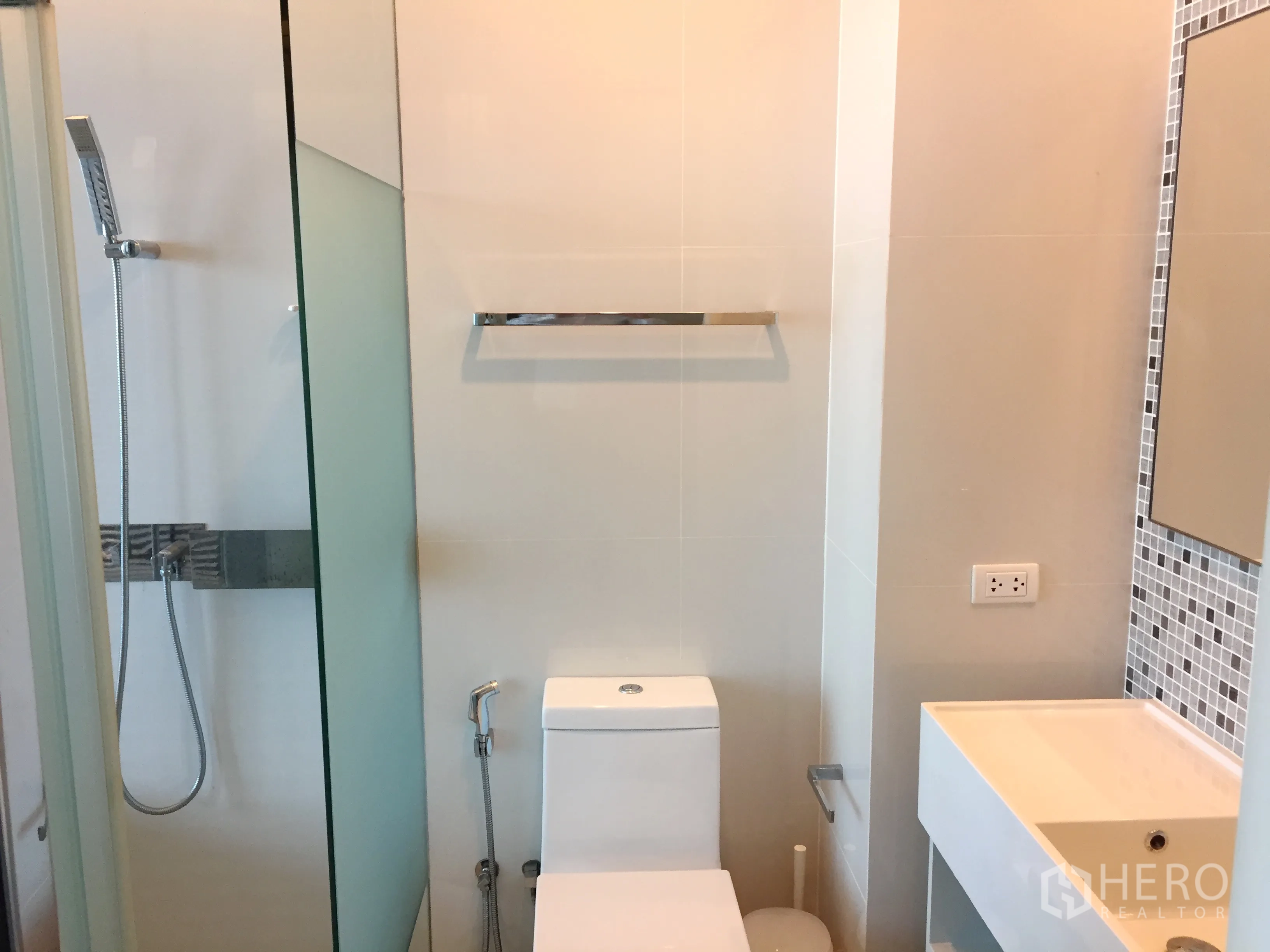 公寓 出租在Watthana, Bangkok - 现代浴室，玻璃淋浴间、白色洗手台与坐便。