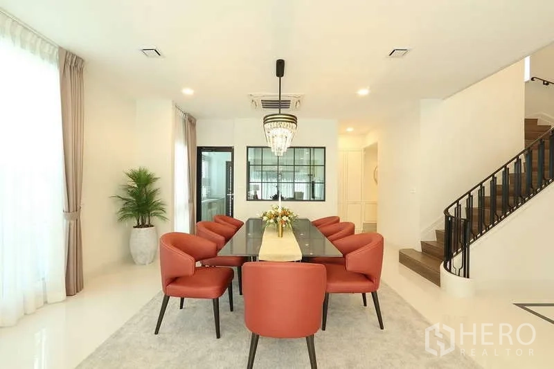 Detached House for rent in Saphan Sung, Bangkok - Dining room with long marble-topped table, eight coral chairs and chandelier.
