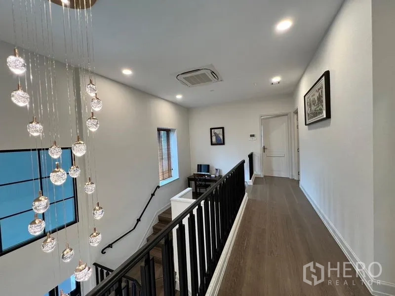 Detached House for rent or sale in Saphan Sung, Bangkok - Upstairs corridor with pendant lights and dark railings.