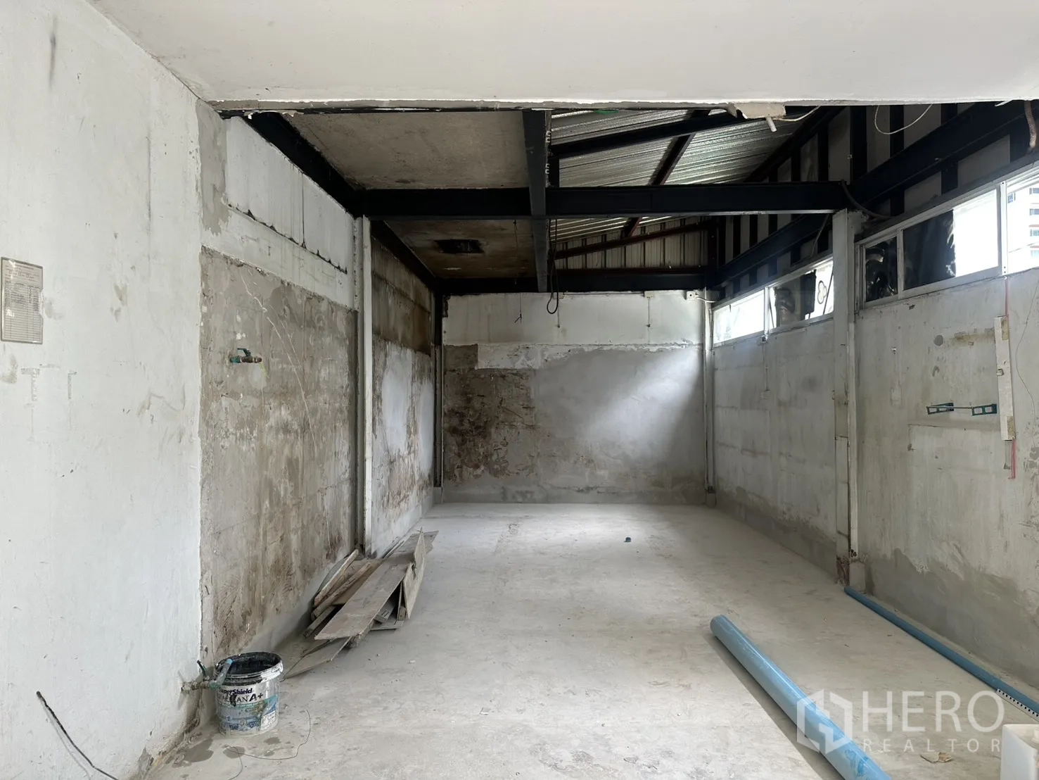 零售空间 for rent in Sathon, Bangkok - 未完工零售空间，混凝土地面、外露钢梁、侧窗采光，地面有施工材料。