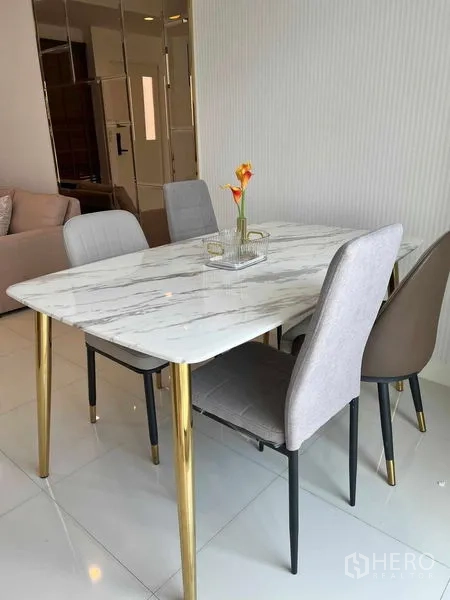 Townhouse for rent in Phra Khanong, Bangkok - Dining area with marble-top table, gold legs and four mixed-color chairs beside the living zone.