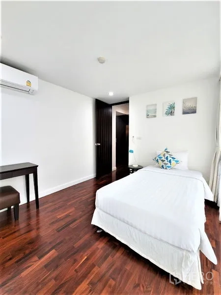 Condominium for rent in Bang Rak, Bangkok - Light-filled guest bedroom with single bed, desk, wall art, air conditioning and wooden floors.