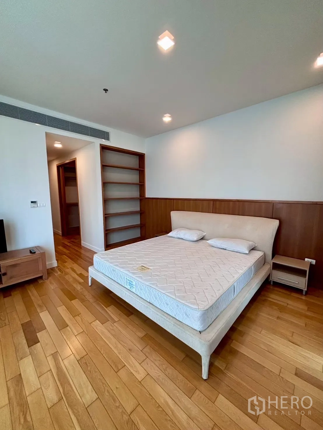 Condominium for rent in Khlong Toei, Bangkok - Spacious master bedroom with wooden floors and open shelving
