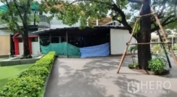 零售空间 出租在Khlong Toei, Bangkok - 绿篱步道通往有顶商铺单元，周围树木茂盛。