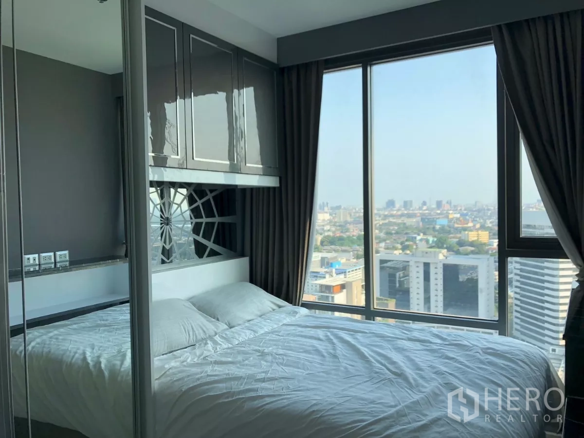 Condominium for rent in Khlong Toei, Bangkok - Second bedroom with built-in cabinets and wide city views through large windows.