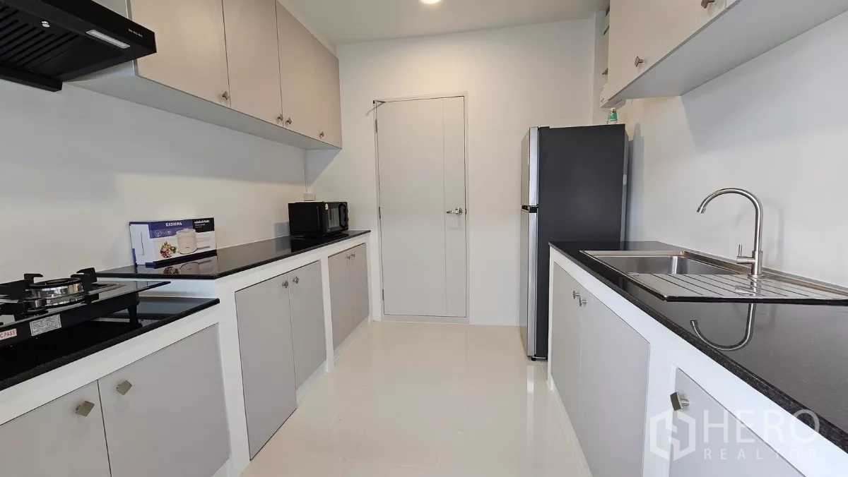 独立式住宅 出租或出售在Bang Phli, Samut Prakan - 封闭式厨房，黑色花岗岩台面，燃气灶、水槽、灰白柜体与冰箱。