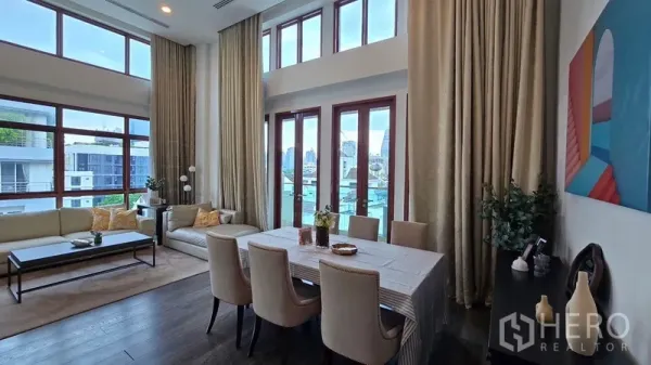 Condominium for rent in Pathum Wan, Bangkok - Double-height living and dining area with floor-to-ceiling windows and city views.