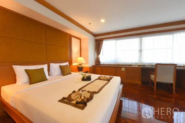 อพาร์ทเมนท์ ให้เช่าในWatthana, Bangkok - ห้องนอนมาสเตอร์เตียงคิงส์ เฮดบอร์ดบุผ้า โคมไฟหัวเตียง และโต๊ะทำงานยาวใต้หน้าต่าง