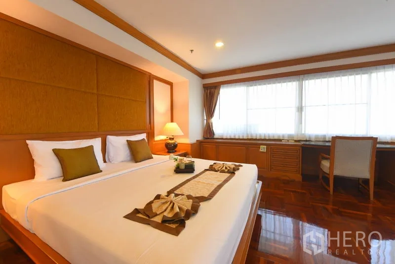 อพาร์ทเมนท์ ให้เช่าในWatthana, Bangkok - ห้องนอนมาสเตอร์เตียงคิงส์ เฮดบอร์ดบุผ้า โคมไฟหัวเตียง และโต๊ะทำงานยาวใต้หน้าต่าง