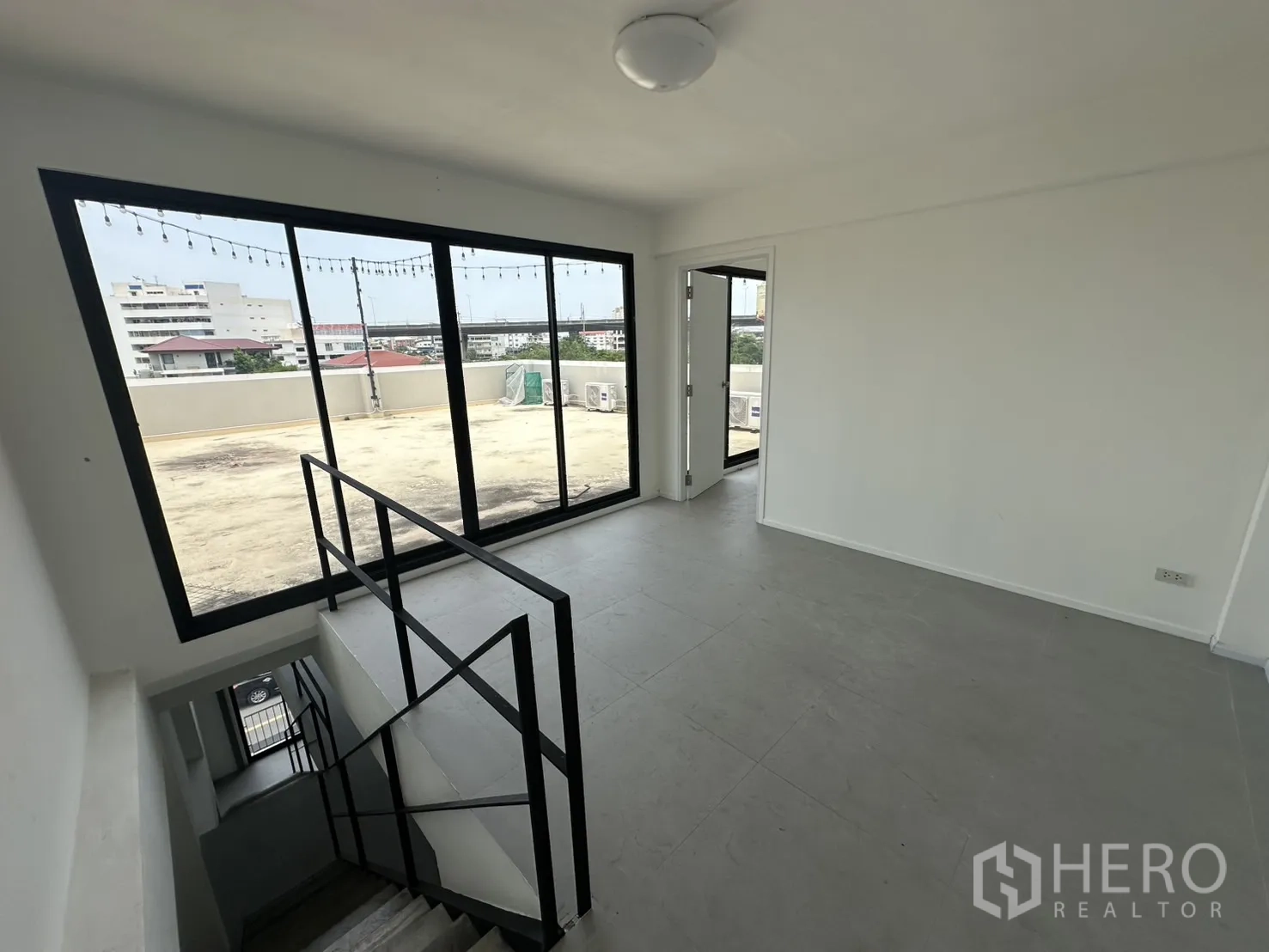 Home Office for rent or sale in Bang Na, Bangkok - Top-floor landing opening to a large rooftop terrace via sliding glass doors.
