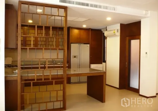 Detached House for rent in Khlong Toei, Bangkok - Warm wood kitchen with granite breakfast counter, partition shelving and a double-door refrigerator.
